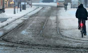 Winter-in-wuerzburg-ein-mann-faehrt-mit-seinem-rad-auf-der-mit-schneematsch-bedeckten-strassenbahnschiene
