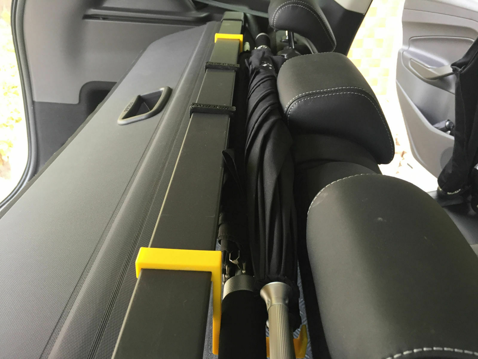 Regenschirmablage zwischen Rücksitzlehne und Kofferraum-Rollo