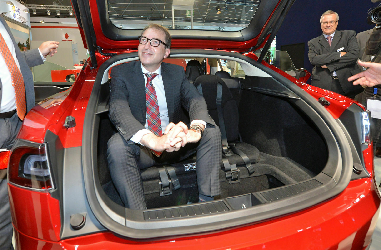 Bundesverkehrsminister Alexander Dobrindt (CSU) auf der Automesse "Auto Mobil International 2014" im Heck eines Tesla S. Die Pkw-Maut könnte laut ihm bis zu 100 Euro jährlich kosten