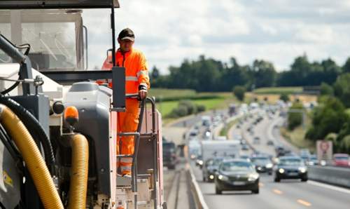 Ein Arbeiter fräst an der A9 in der Nähe von Allershausen mit einer Maschine die alte Fahrbahndecke ab