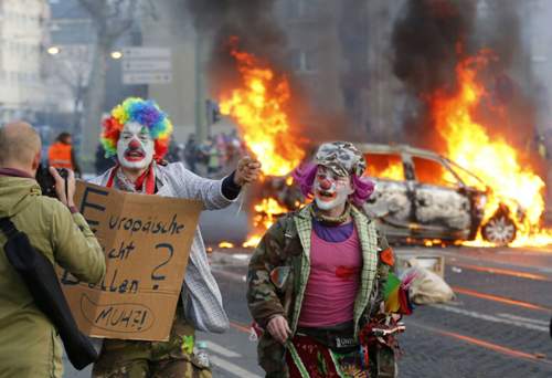 Als Clown verkleidete Demonstranten vor brennenden Autos in Frankfurt