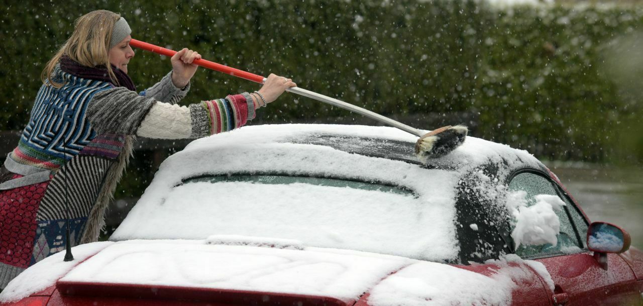 Statt ihr Cabrio offen zu fahren fegt sie Schnee vom Auto: Diese Dame im bayrischen Nesselwang hatte sich das Osterwochenende sicher anders vorgestellt