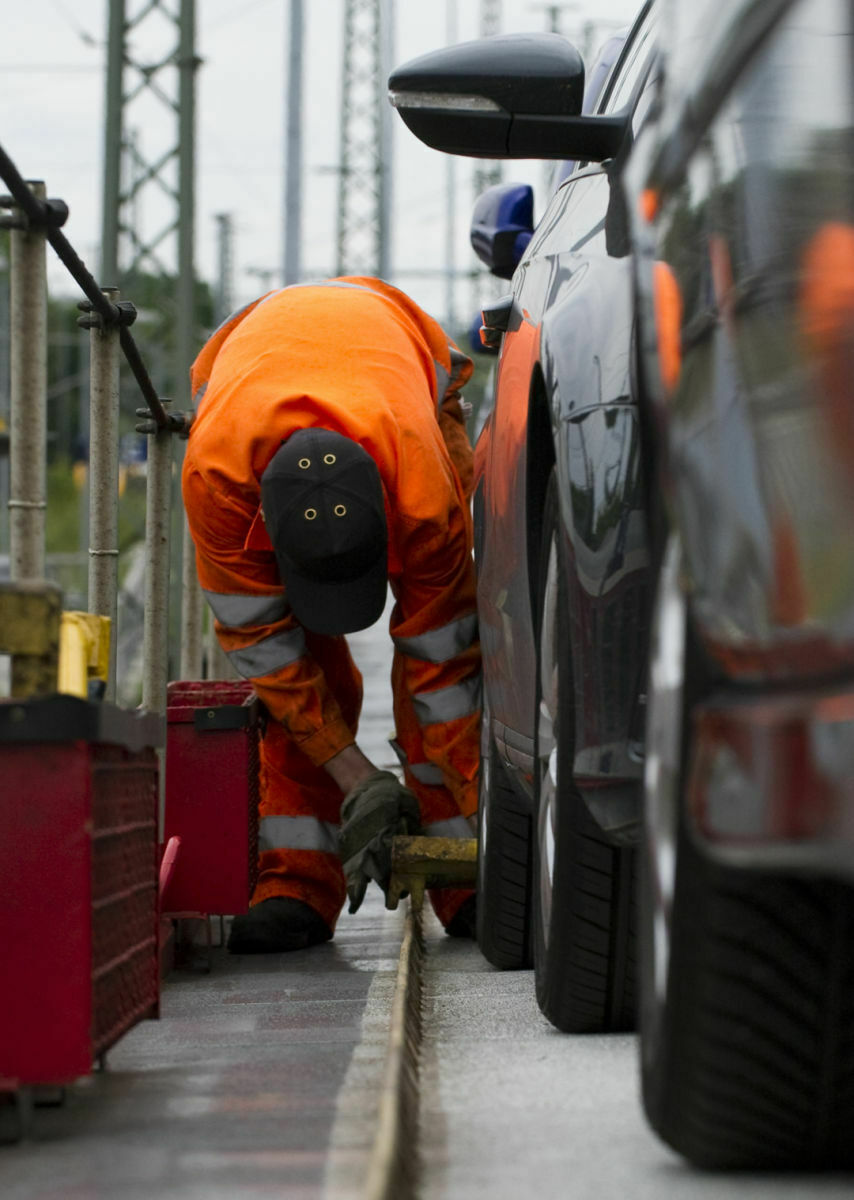 Ein Bahnmitarbeiter sichert die Autos vor Fahrtbeginn