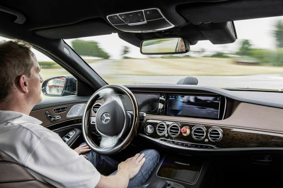 Ein Mercedes-Entwickler legt in der autonom fahrenden S-Klasse die Hände in seinen Schoß