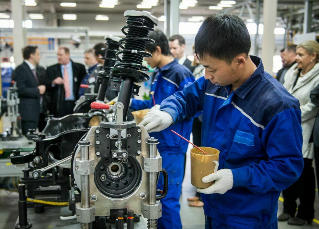 ZF-Mitarbeiter in Peking montieren Fahrwerkskomponenten an eine Vorderachse für Mercedes