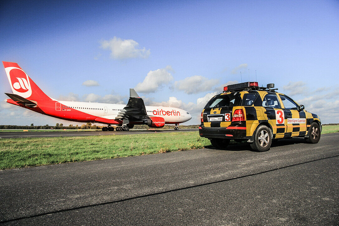 Ein Marshaller-Auto und ein Flugzeug m Düsseldorfer Flughafen