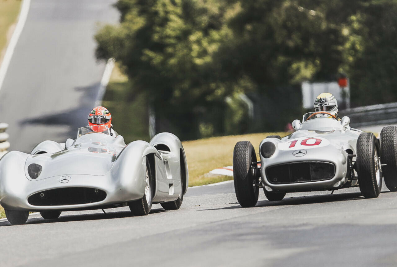 Der britische Formel-1-Fahrer Lewis Hamilton (l) und der Deutsche Nico Rosberg sitzen am 04.07.2013 bei einem Pressetermin in historischen Silberpfeil-Rennwagen vom Typ W 196 und W 154
