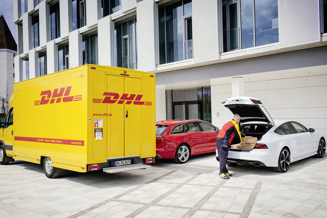 Paketlieferung in praktisch: Aus dem DHL-Transporter in den Kofferraum des Audi