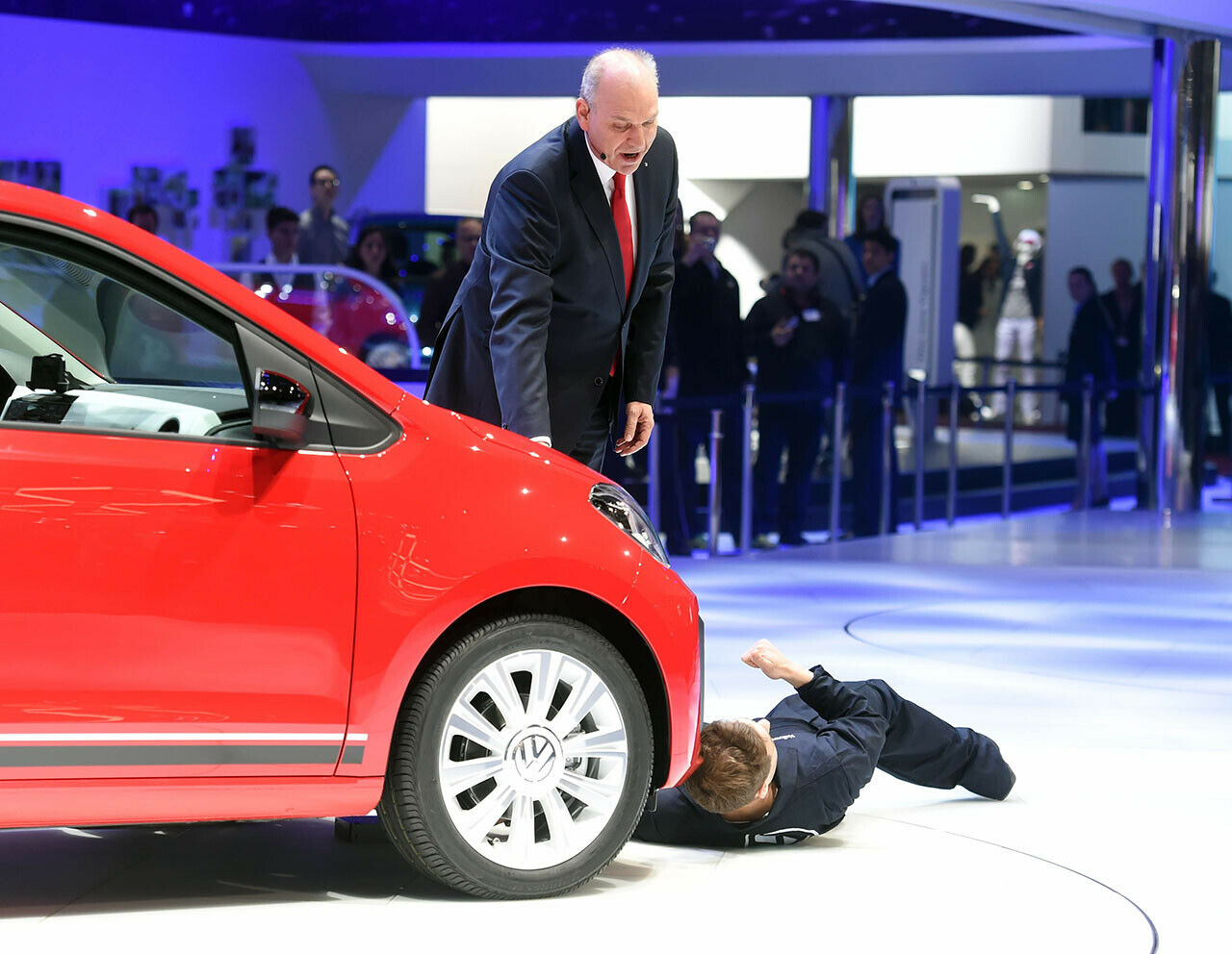 Der britische Comedian bei der Störaktion unterm VW Up. Im Hintergrund ist Jürgen Stackmann, VW Vorstand für Verkauf und Marketing zu sehen