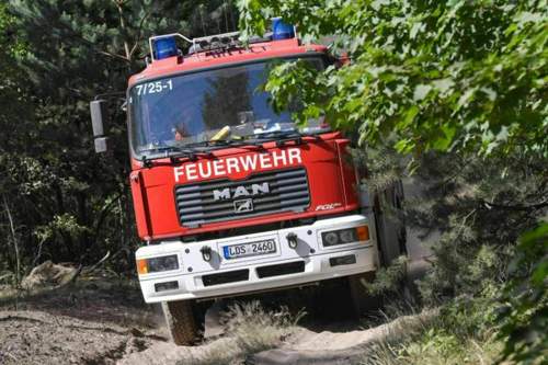 Ein-feuerwehrfahrzeug-faehrt-ueber-einen-sandweg-zum-waldbrand-in-der-lieberoser-heide