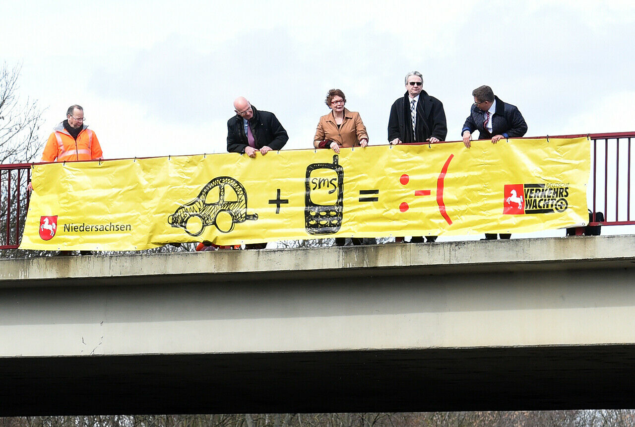 Vertreter der Verkehrswacht, der Landesregierung von Niedersachsen, der Polizei und Wirtschaft präsentiert ein Banner der Aktion "Tippen tötet"