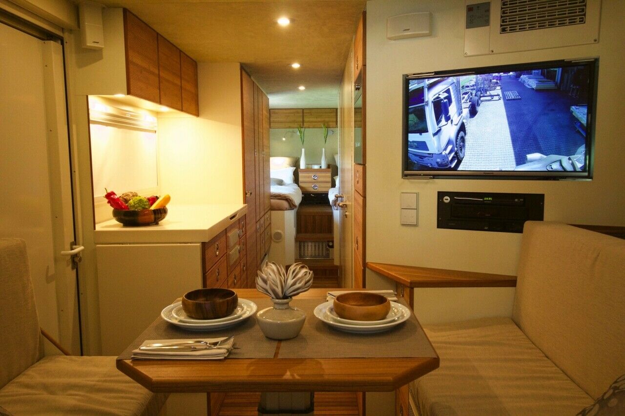 Ein Auto wie ein Appartment: Blick vom Esszimmertisch auf Fernseher, Küchenanrichte und Schlafzimmer
