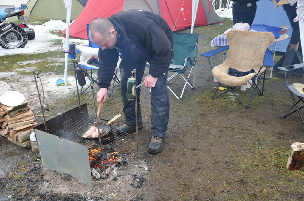 Dieser Mann bereitet sich sein Abendessen auf einer windgeschützten Grill-Konstruktion.