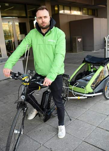 Daniel Moser, Verkehrsexperte bei Greenpeace, sitzt auf einen E-Bike mit Anhänger und eingebaute Stickoxid-Messeinrichtung.
